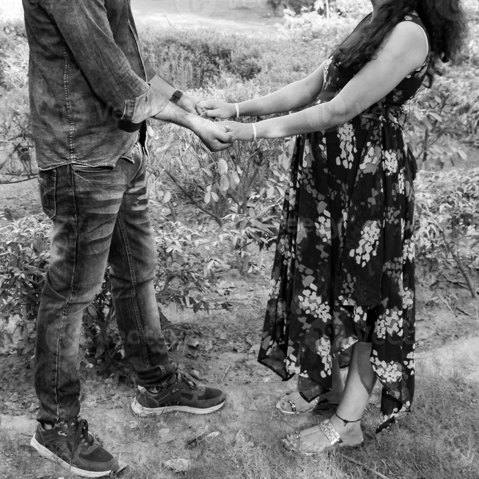 Indian couple posing for maternity baby shoot. The couple is posing in a lawn with green grass and the woman is falunting her baby bump in Lodhi Garden in New Delhi, India - Black and White photo