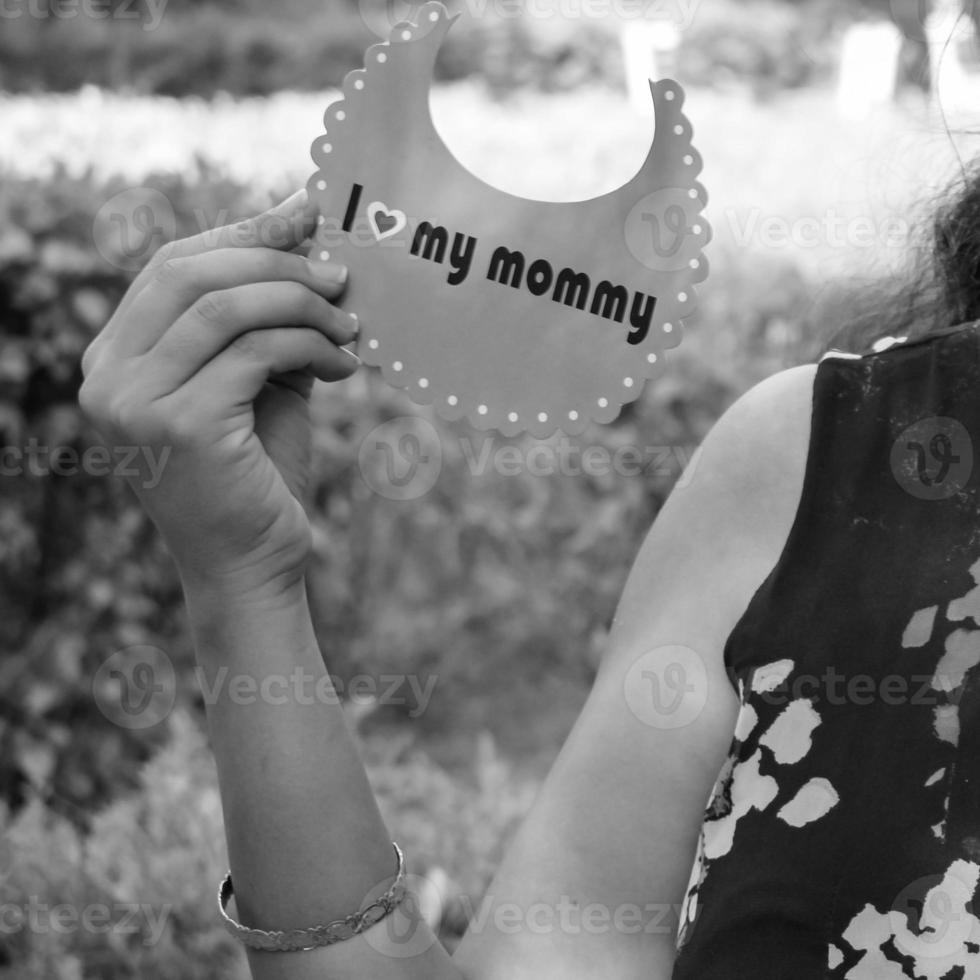 Indian couple posing for maternity baby shoot. The couple is posing in a lawn with green grass and the woman is falunting her baby bump in Lodhi Garden in New Delhi, India - Black and White photo