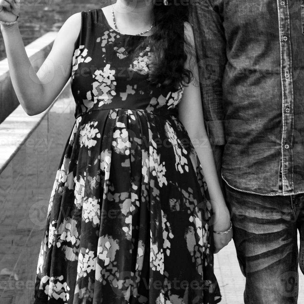 pareja india posando para una sesión de fotos de maternidad. la pareja está posando en un césped con hierba verde y la mujer está faluntando su panza en el jardín de lodhi en nueva delhi, india - blanco y negro