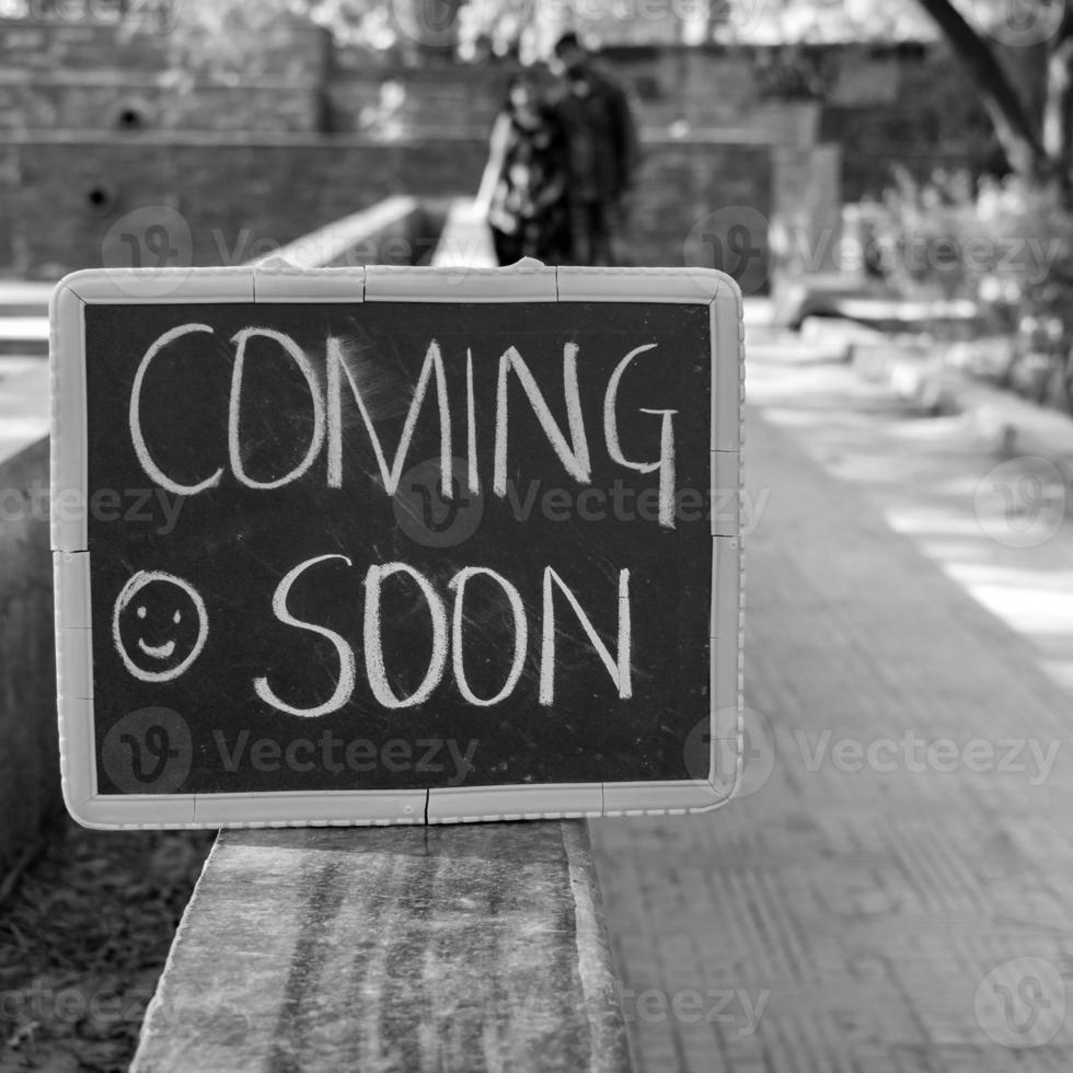 Indian couple posing for maternity baby shoot. The couple is posing in a lawn with green grass and the woman is falunting her baby bump in Lodhi Garden in New Delhi, India - Black and White photo