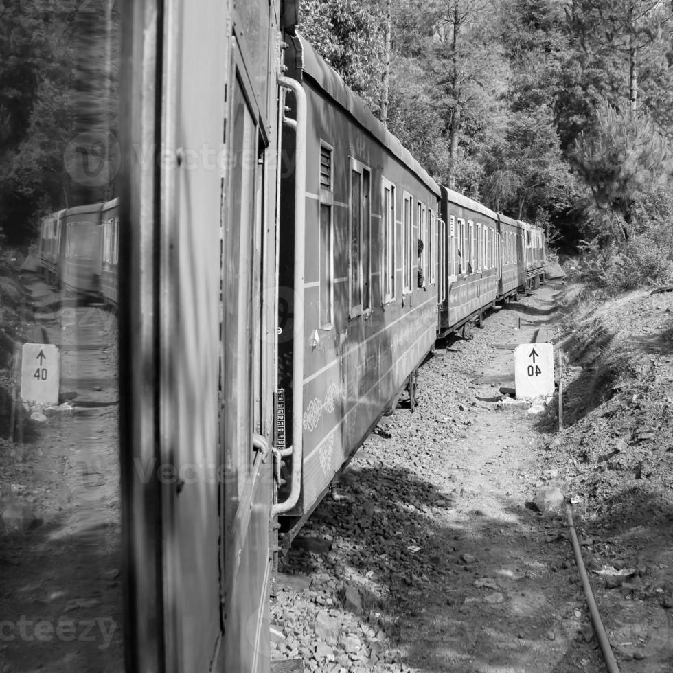 Toy Train moving on mountain slope, beautiful view, one side mountain, one side valley moving on railway to the hill, among green natural forest.Toy train from Kalka to Shimla in India-Black and White photo