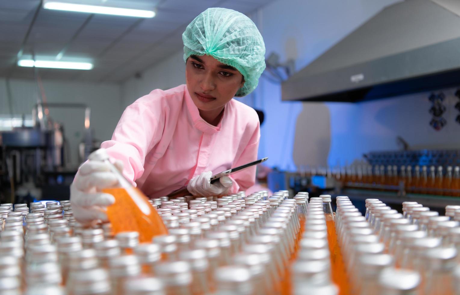 Product quality control staff at the fruit juice production line Perform product quality checks To ensure that the products produced are of good quality photo