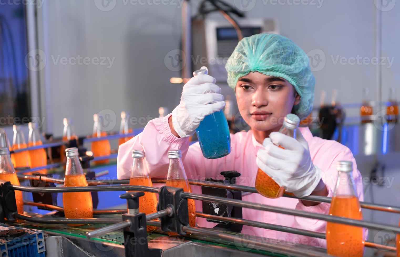 Product quality control staff at the fruit juice production line Perform product quality checks To ensure that the products produced are of good quality photo