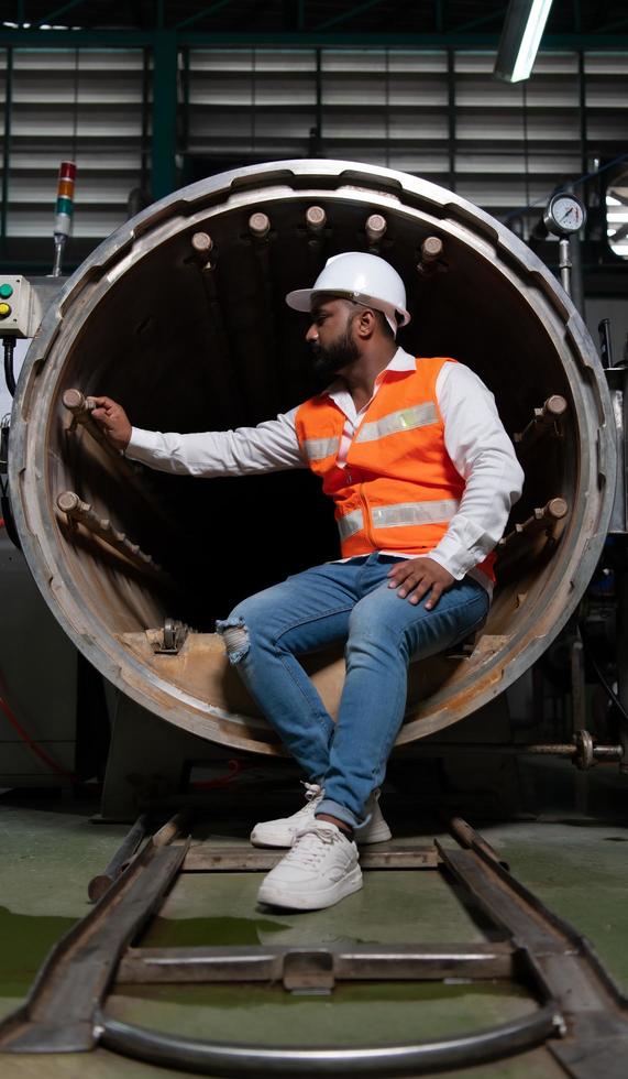 el ingeniero jefe de la planta mecánica realiza la inspección del túnel de la máquina de esterilización. para comprobar el estado de funcionamiento de la máquina para estar listo foto