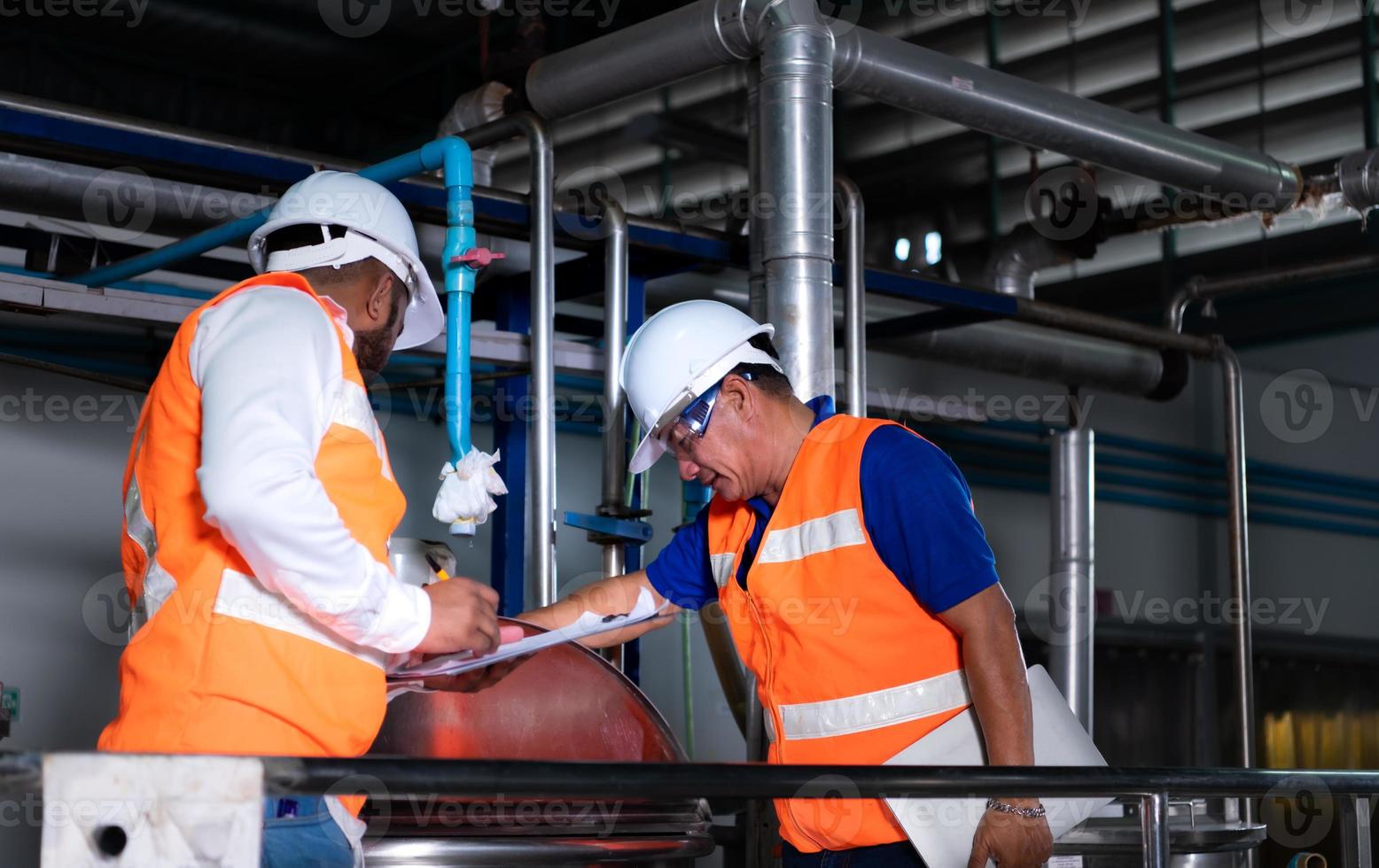 ingeniero jefe de una planta mecánica inspeccionando y explicando el mantenimiento de la máquina al mecánico foto