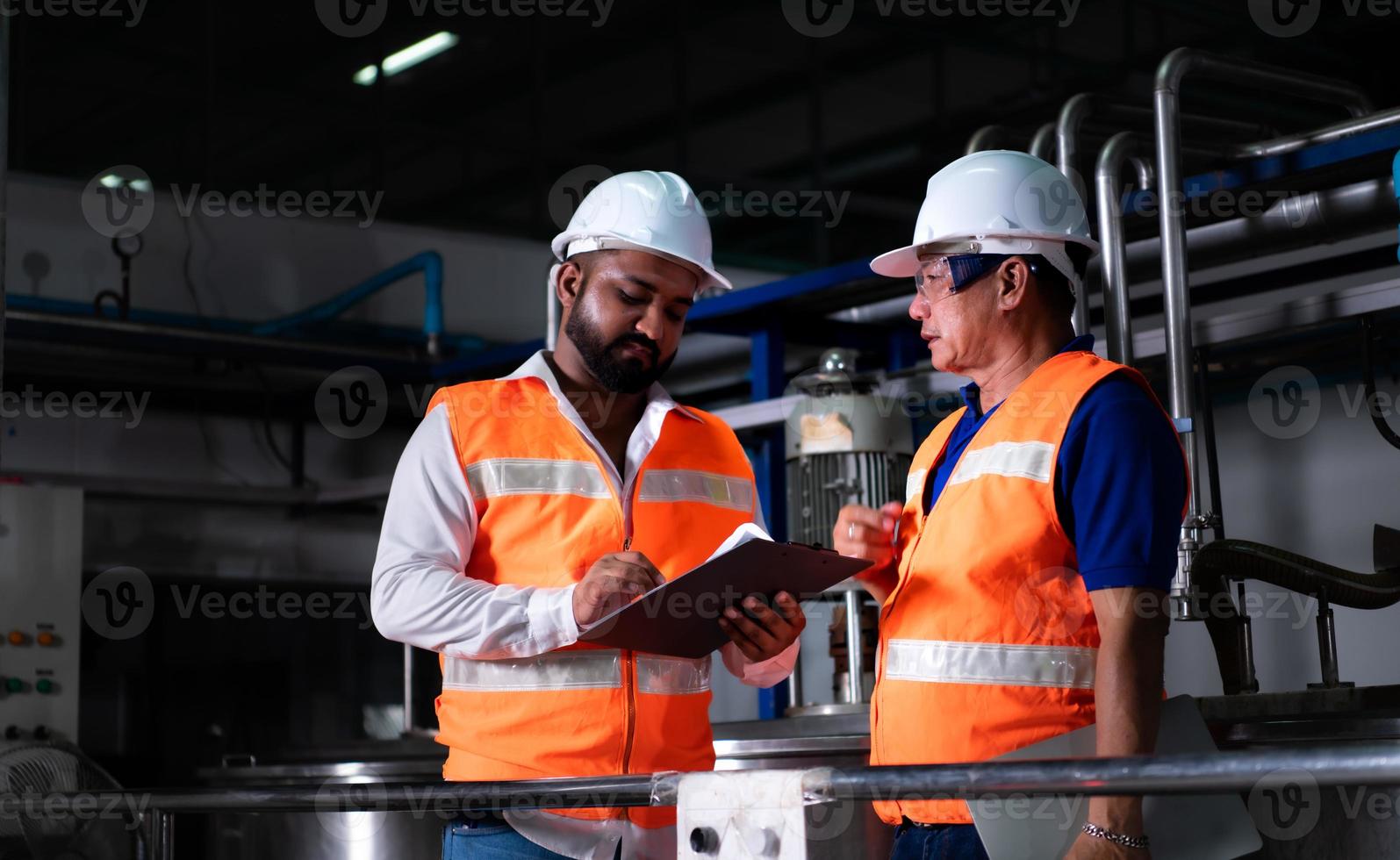 ingeniero jefe de una planta mecánica inspeccionando y explicando el mantenimiento de la máquina al mecánico foto