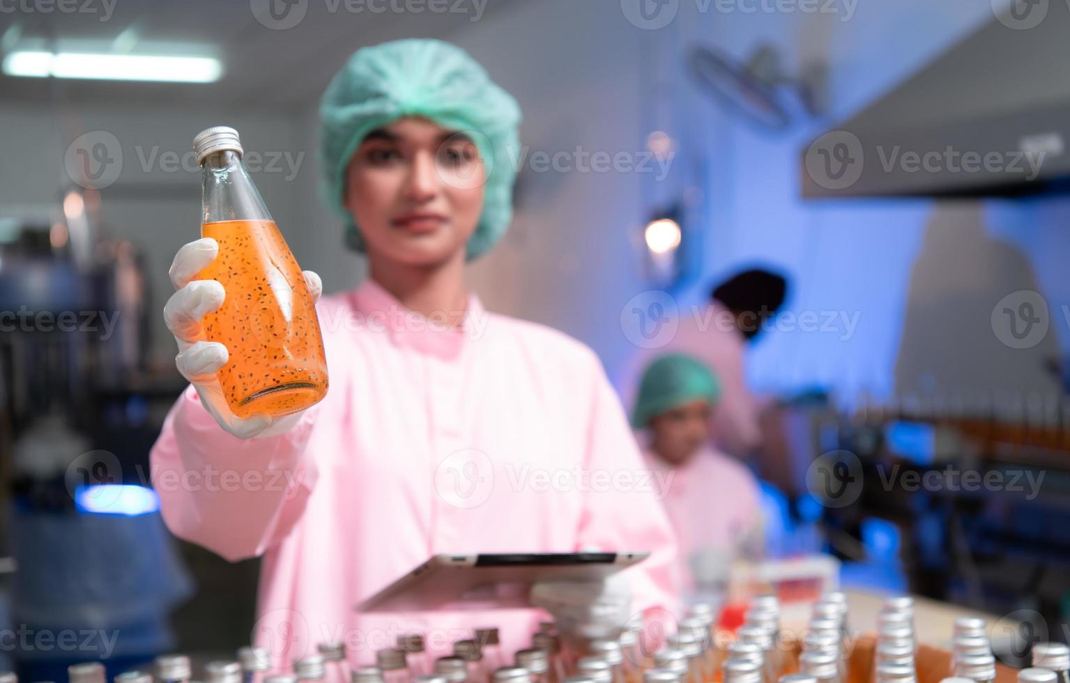 Product quality control staff at the fruit juice production line Perform product quality checks To ensure that the products produced are of good quality photo