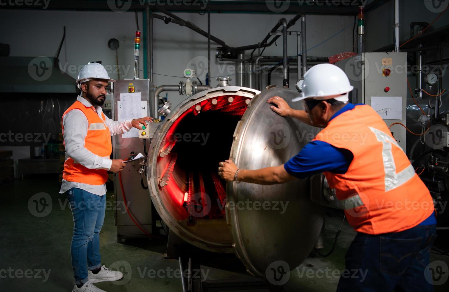 ingeniero jefe de una planta mecánica inspeccionando y explicando el mantenimiento de la máquina al mecánico foto