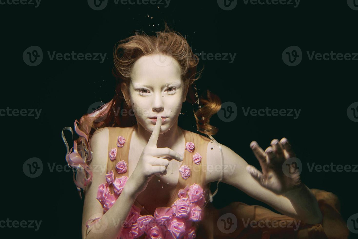 Young redhead girl in dress made of roses underwater photo