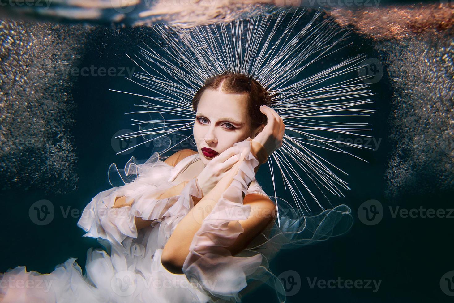 bella mujer con labios rojos y joyería femenina bajo el agua como la virgen maría foto