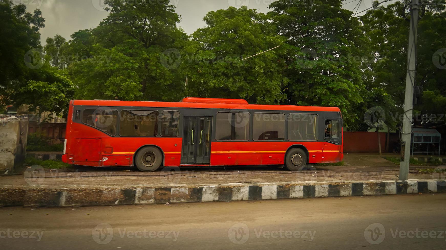 red colored bus parked on the side of the road photo