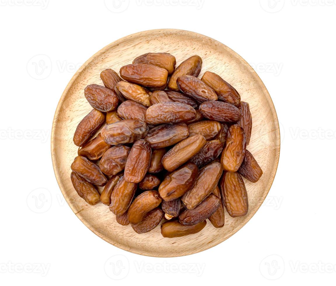dry dates palm in wooden bowl isolated on white background. photo