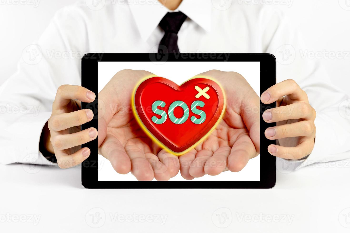 Businessman holding a tablet with heart and write the word sos photo