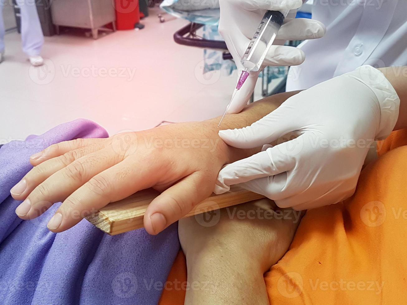 doctor pierces wrist with a syringe for injection,broken wrist from accident photo