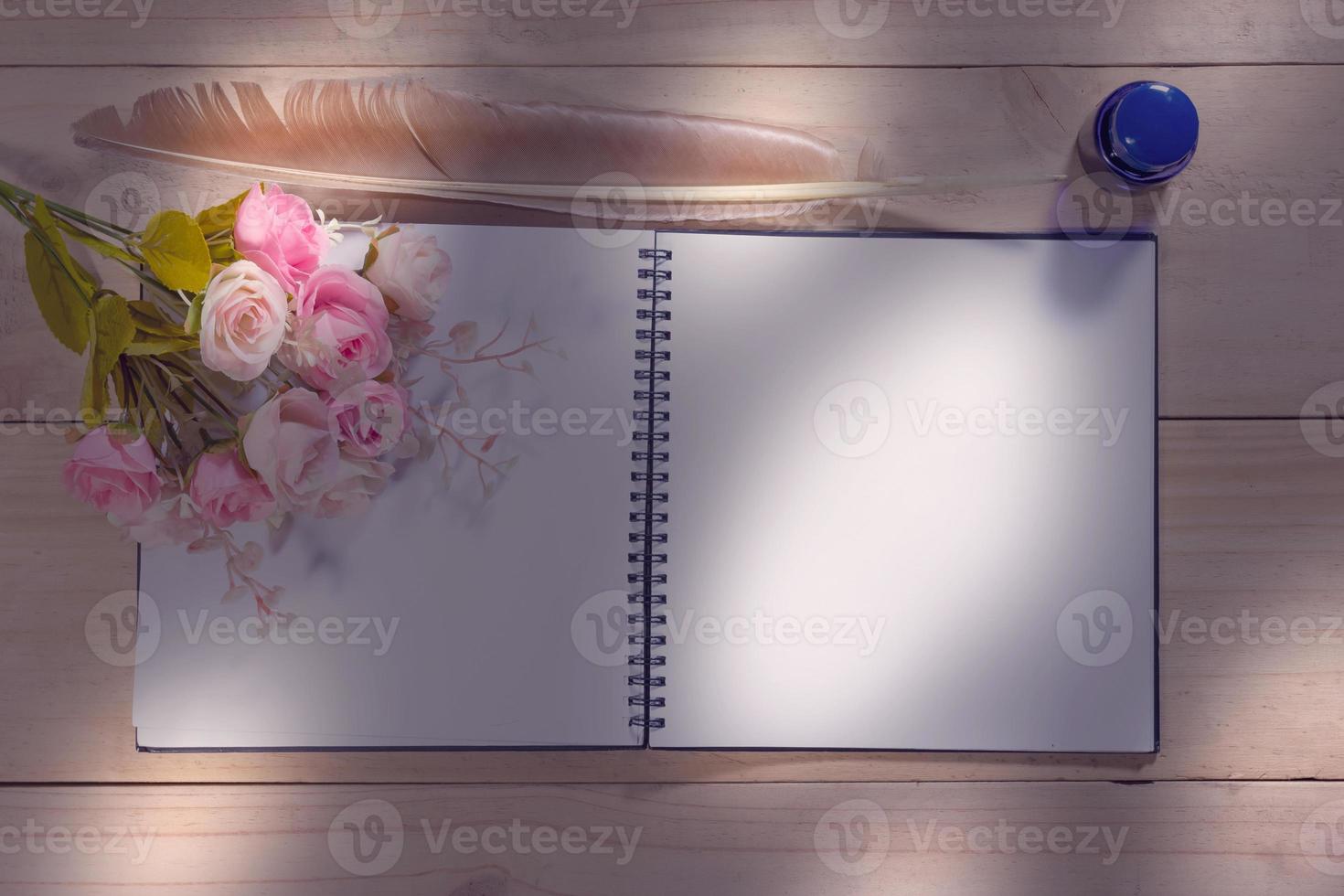 open note book with feather pen on the wood table photo