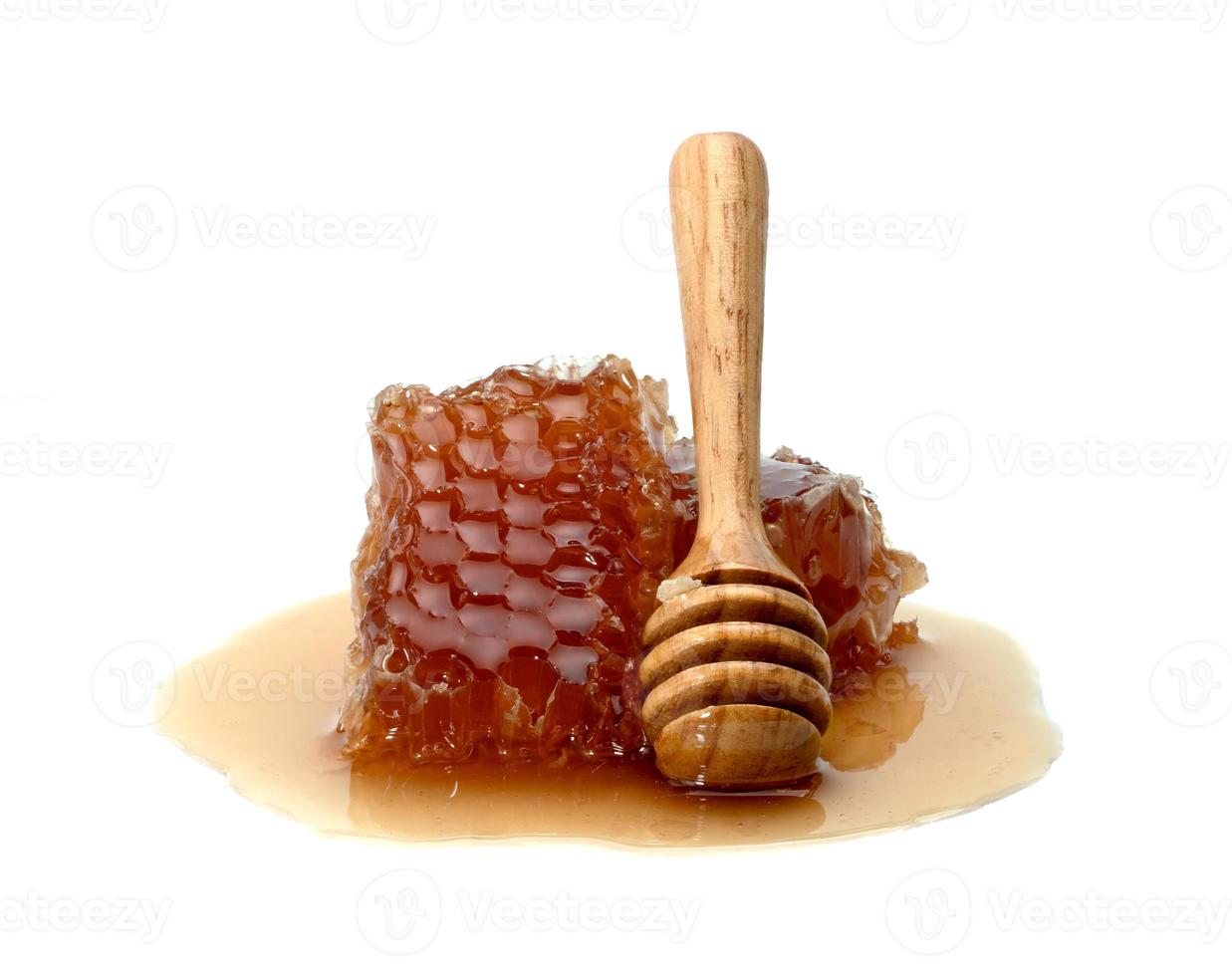 Rebanada de panal fresco y cucharón de miel de madera aislado sobre fondo blanco. foto