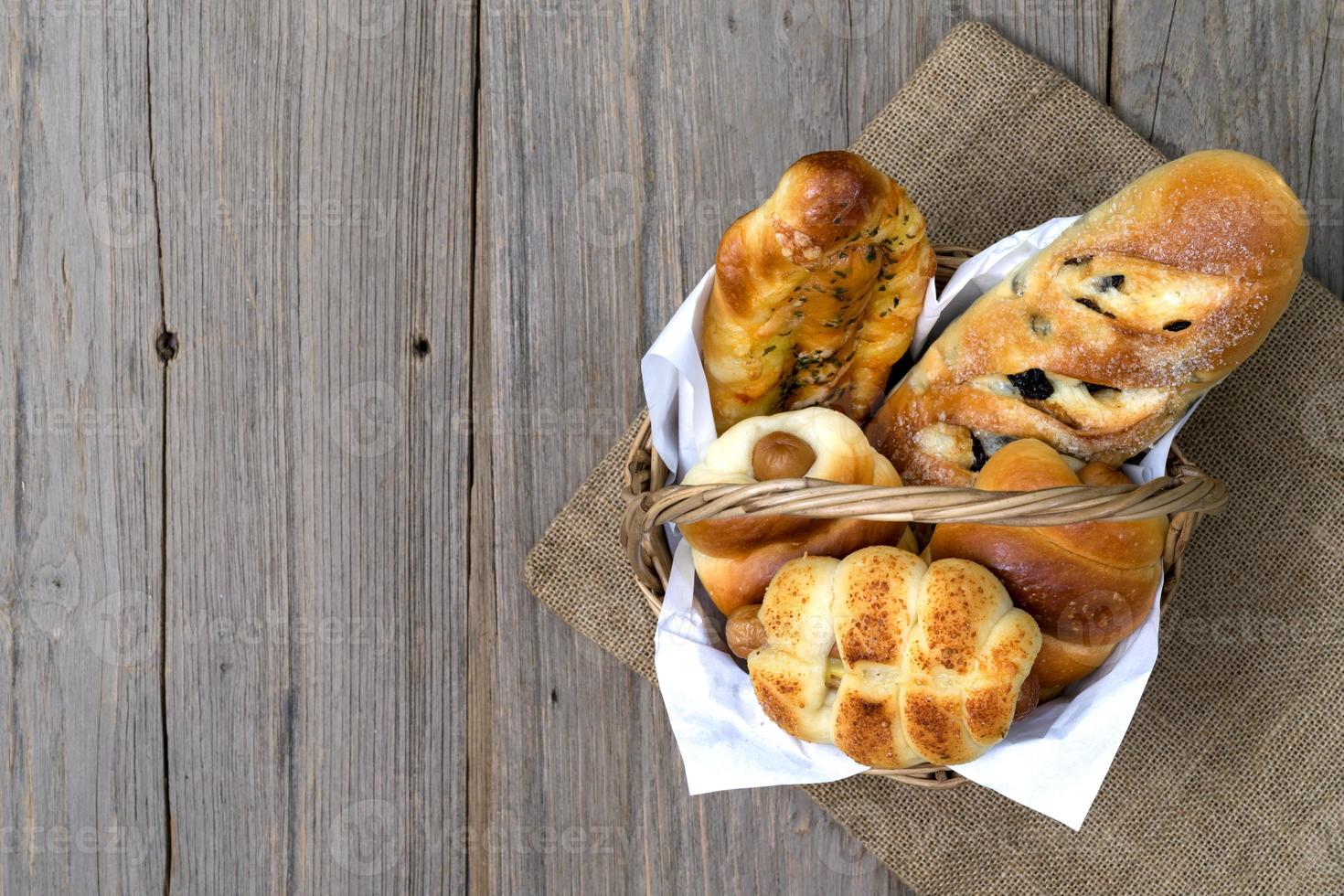 various fresh cheese sausage bread In the basket on wooden background,top view photo