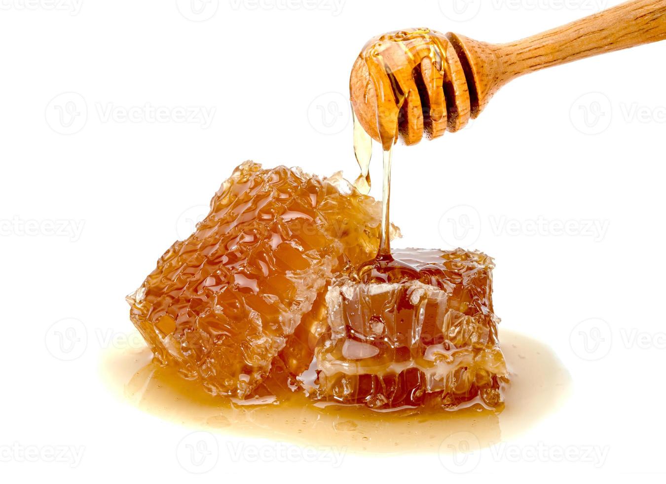 Rebanada de panal fresco y cucharón de miel de madera aislado sobre fondo blanco. foto
