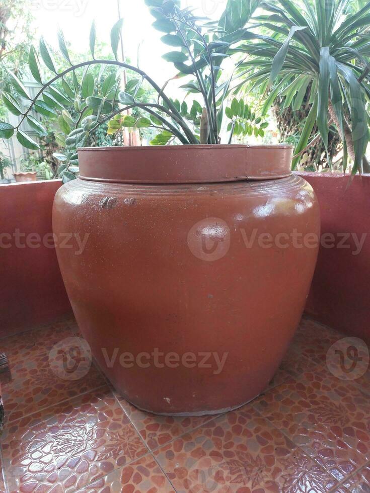 Big earthen jar made of brown terracotta was placed in front of the house near the garden, bright background. photo