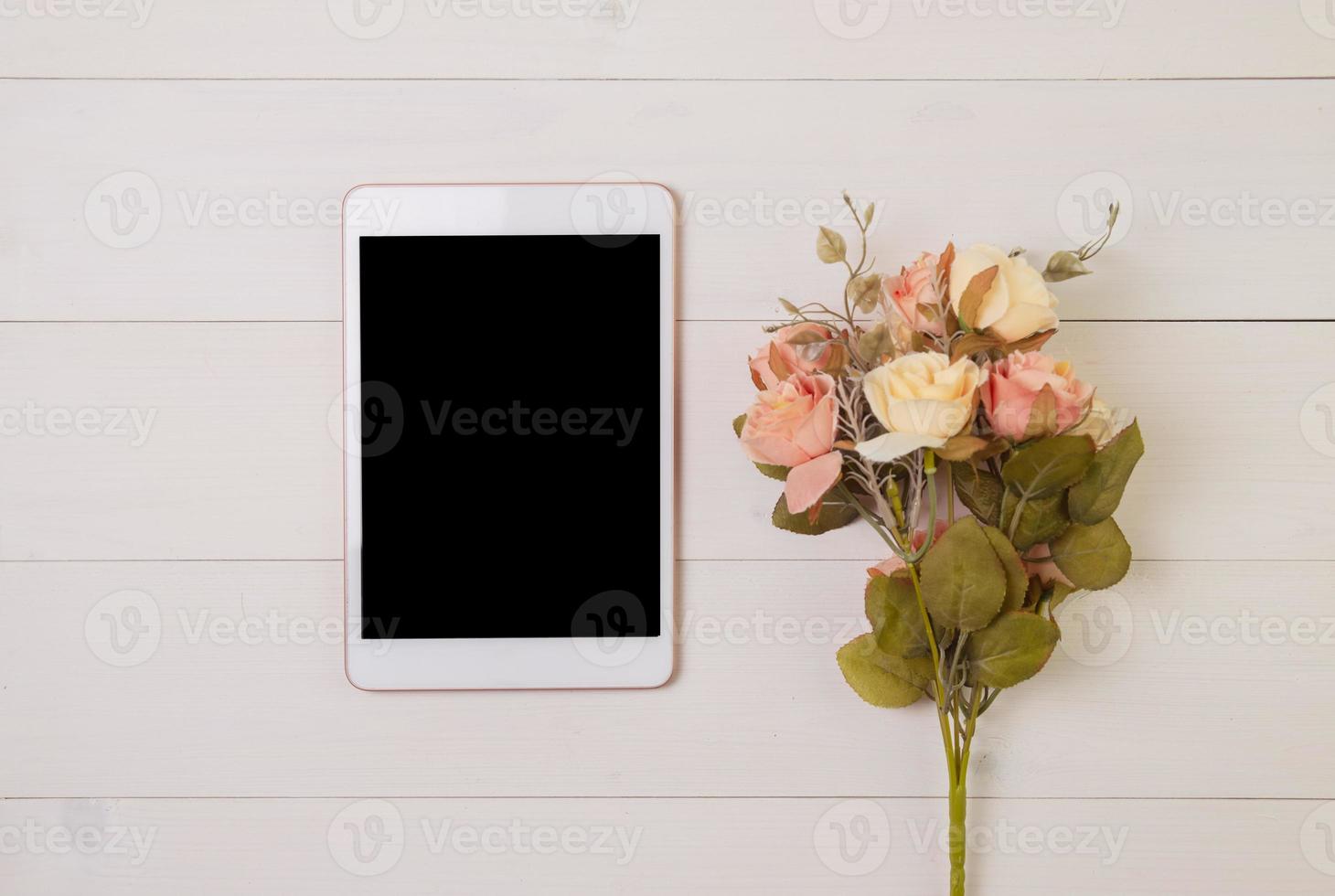 Happy mother day or valentine day with tablet display blank and flower on wooden table pastel tone, feeling romantic with decoration, present festive with on desk, top view, holiday concept. photo