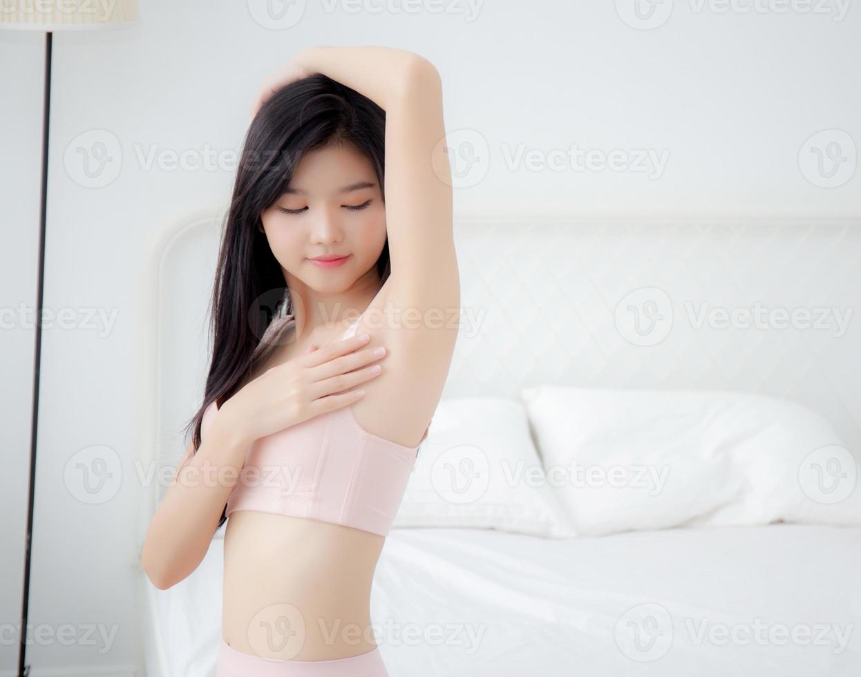 hermosa joven asiática en ropa interior aplicando crema y loción en la axila, la chica de belleza es delgada, feliz, toca la piel de la axila y la depilación para el cuidado corporal, el tratamiento, la cosmética y la limpieza. foto