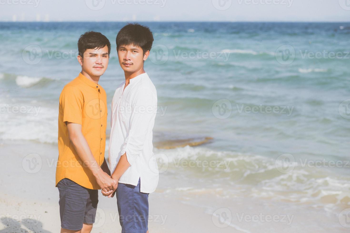 Homosexual portrait young asian couple standing together on beach in summer, asia gay holding hands going sea for leisure and relax with romantic and happy in vacation at sea, LGBT with legal concept. photo