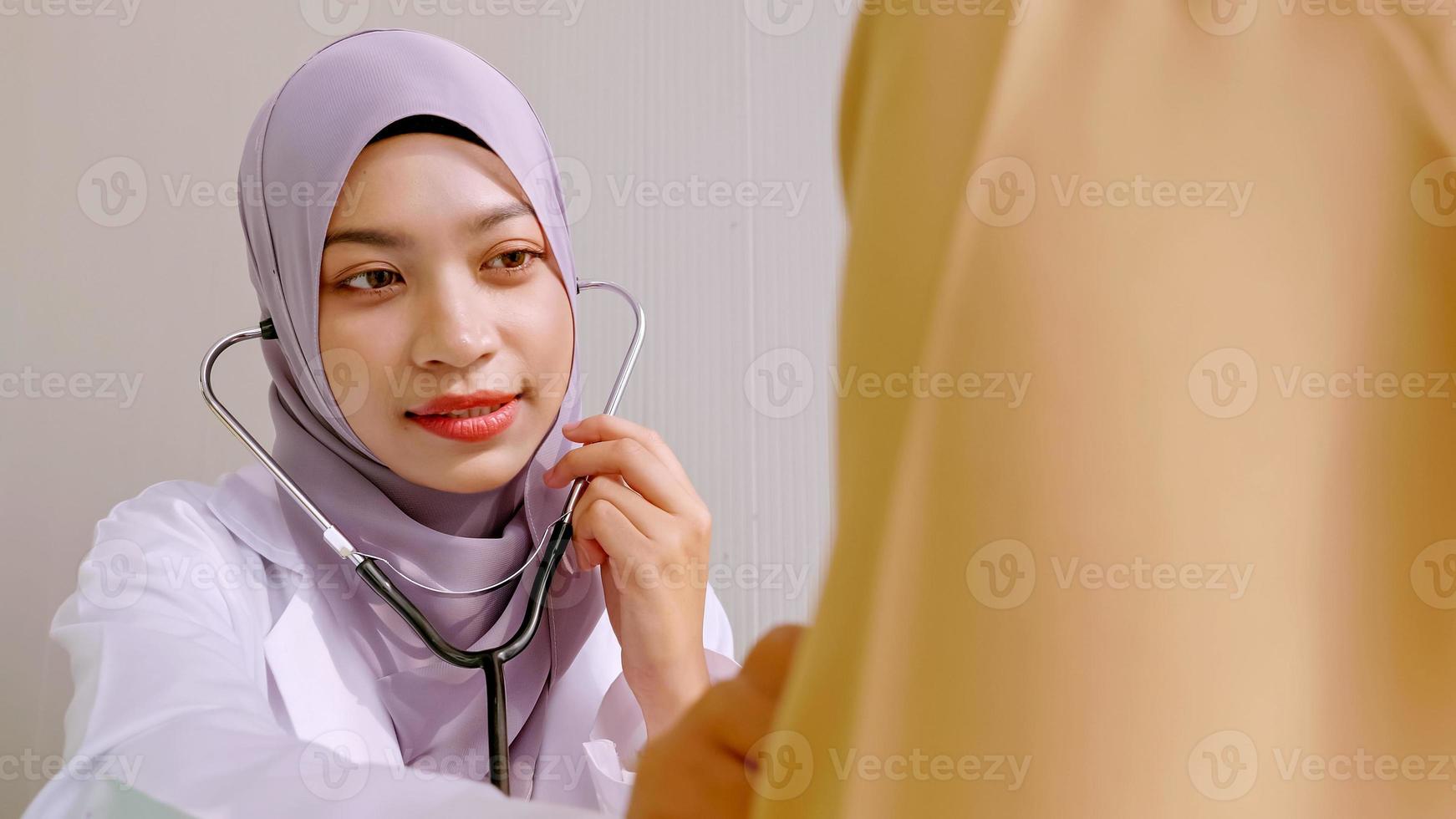 Muslim female doctor checking up patient's health at hospital room. photo