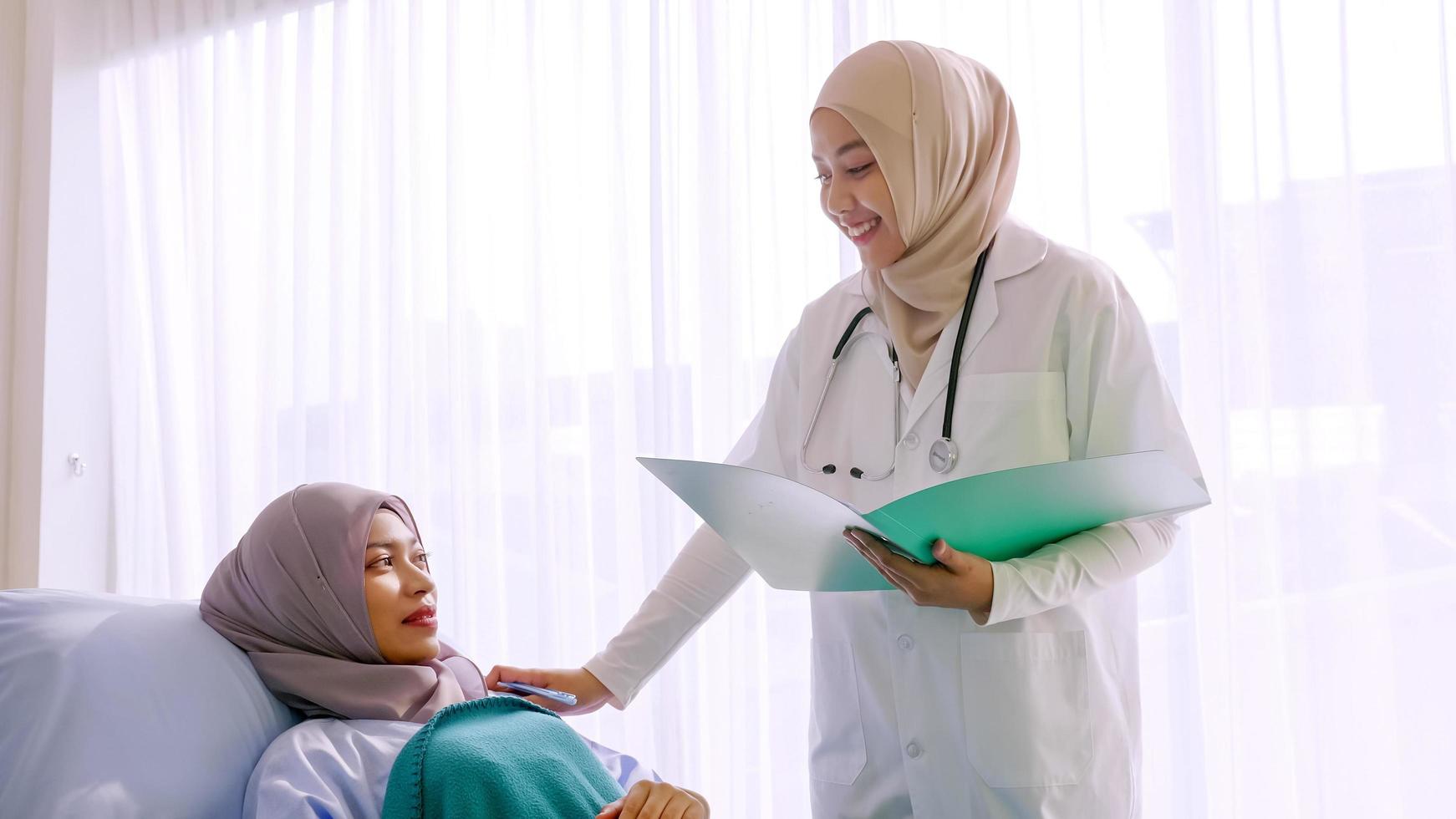 Muslim female doctor taking care of patient at hospital room. photo
