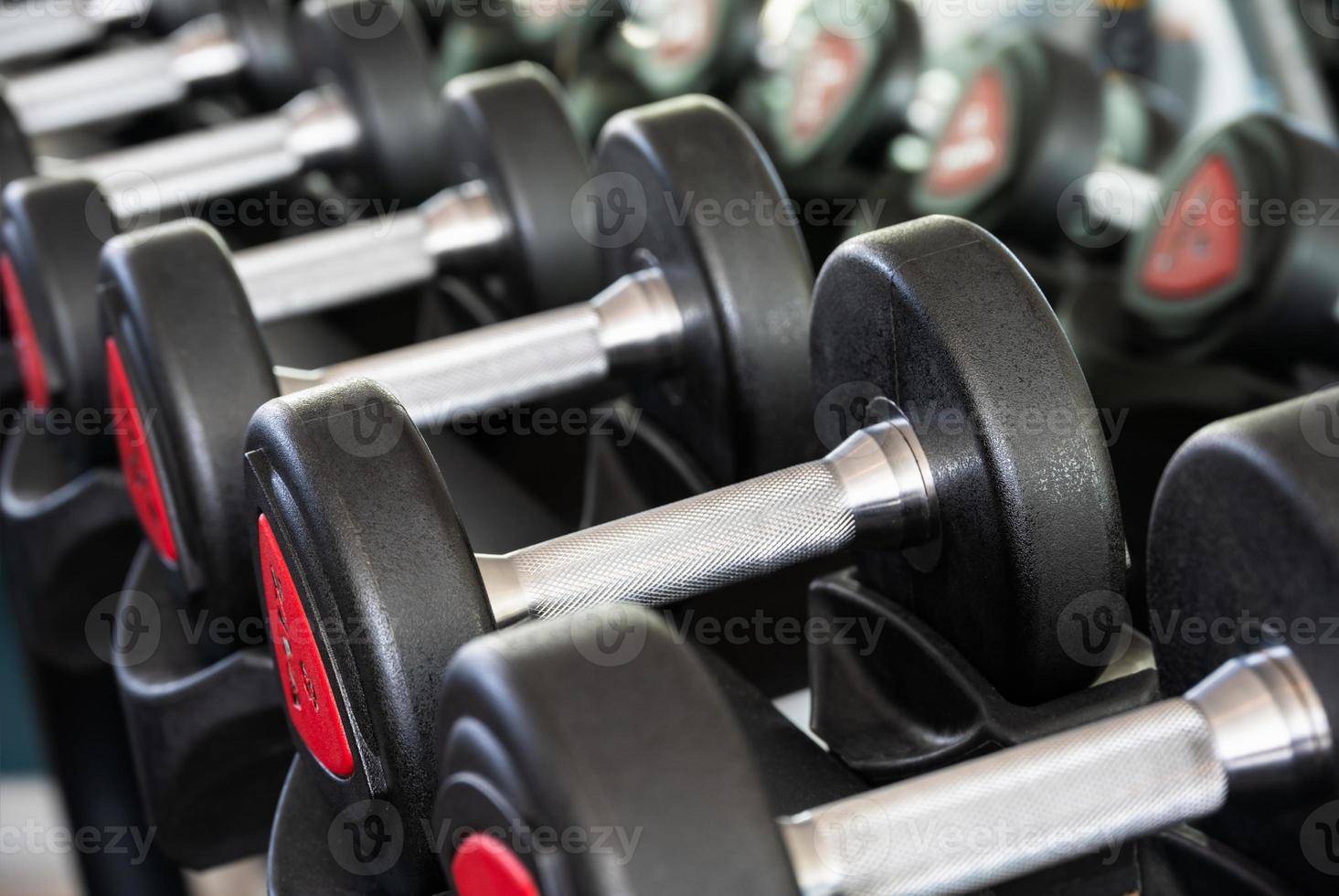 Row of metal dumbbells on rack in sports club for weight training photo