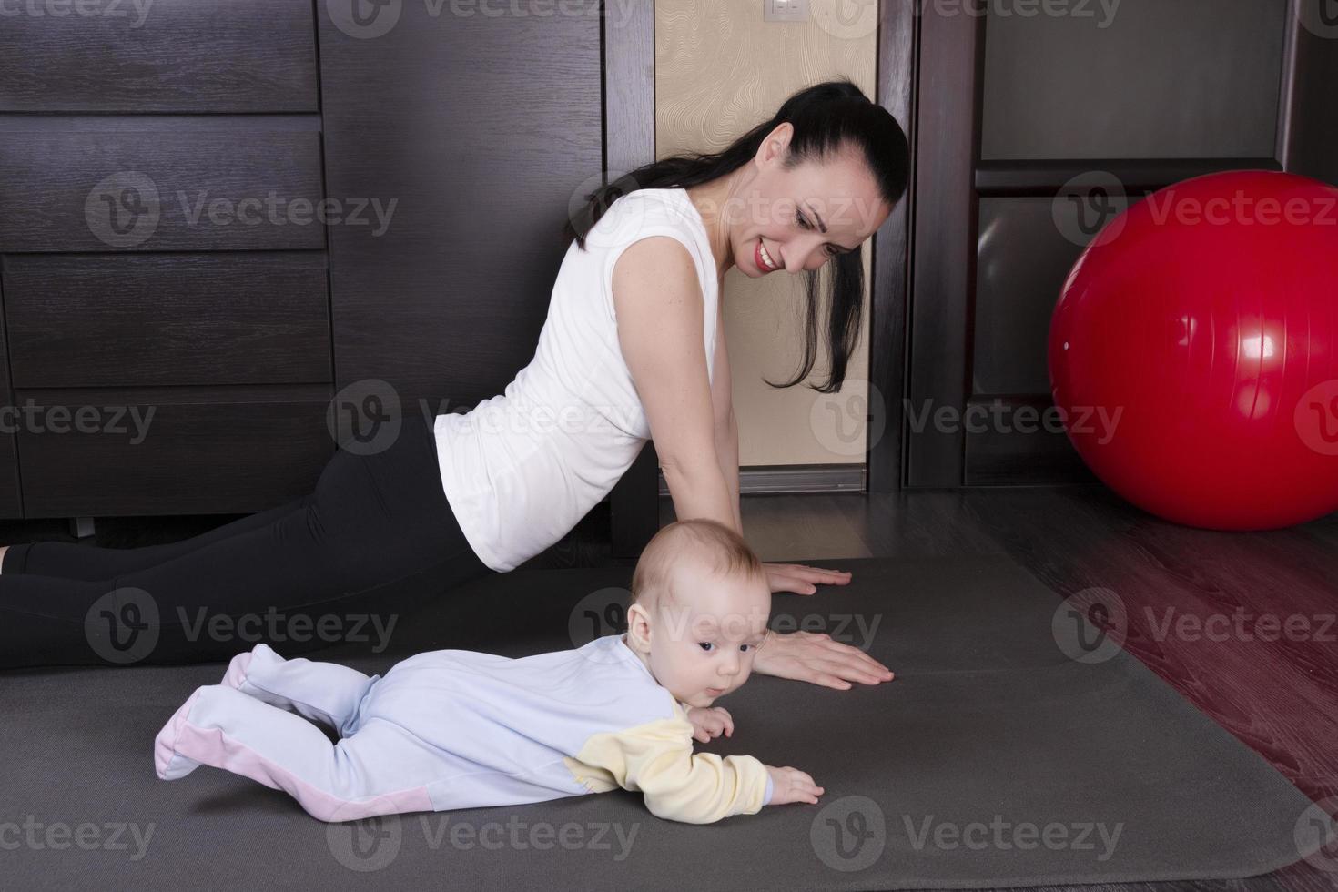A beautiful young mother with her son goes in for sports, yoga, exercises, physical education. The concept of physical recovery after childbirth. photo