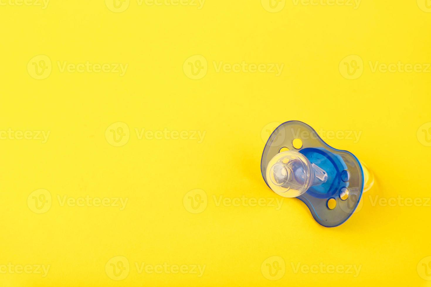 Blue baby silicone pacifier, on a yellow background. Copy space. photo