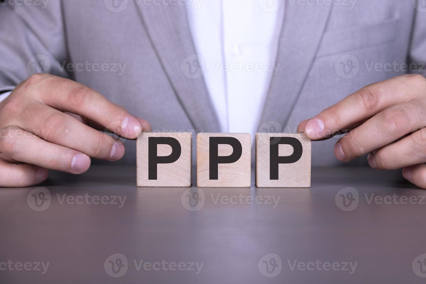 Paycheck Protection Program PPP, the word is written on wooden cubes, blocks on the background of a man, a businessman in a gray suit. photo