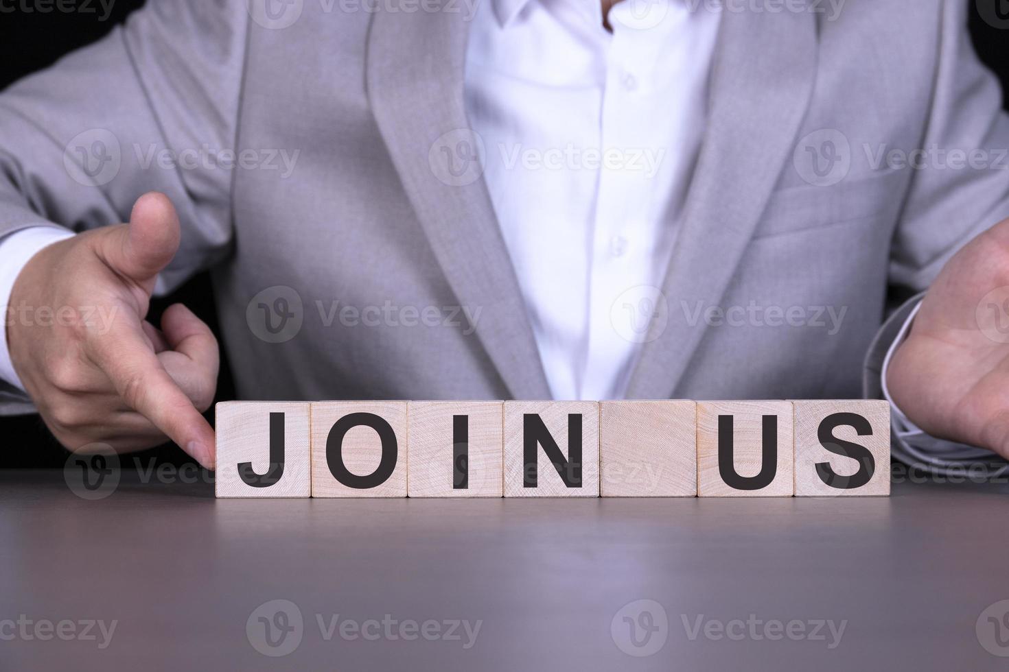 JOIN US, the word is written on wooden cubes, blocks on the background of a man, a businessman in a gray suit. photo