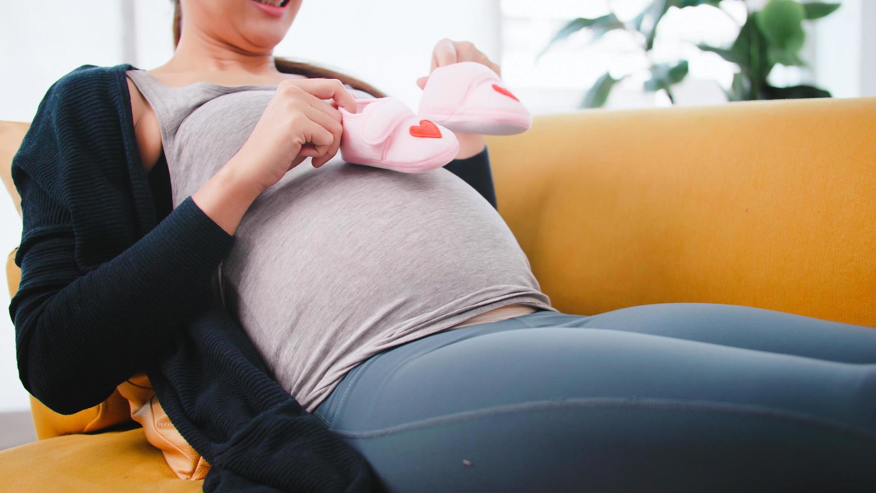 Beautiful Asian pregnant woman is preparing clothes for her newborn baby. photo