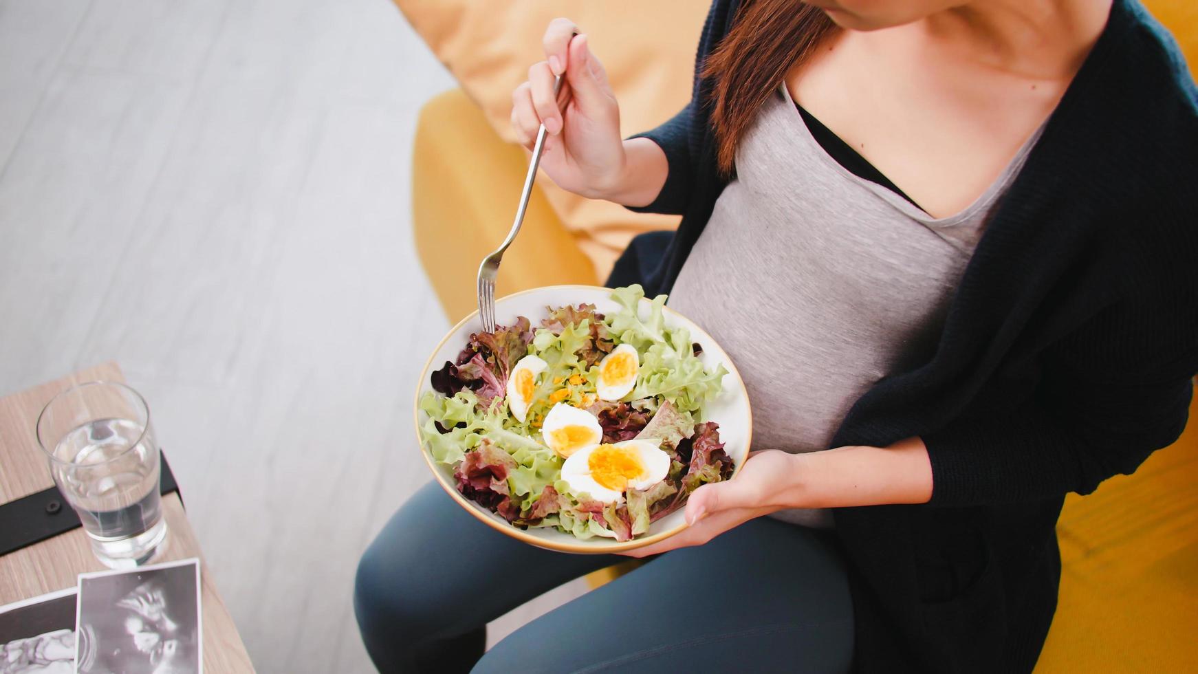 Happy Asian pregnant woman eats healthy food for her unborn baby. photo