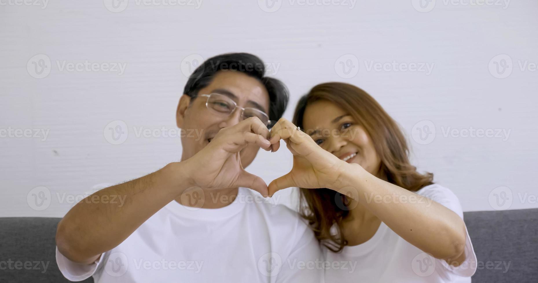 Happy couple doing hand heart together at the room. photo