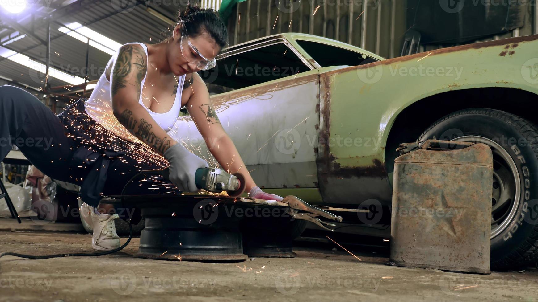 Attractive young woman mechanical worker repairing a vintage car in old garage. photo