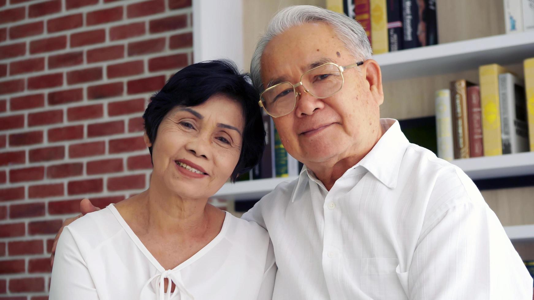 retrato de una feliz pareja asiática de ancianos sentada en un sofá. foto