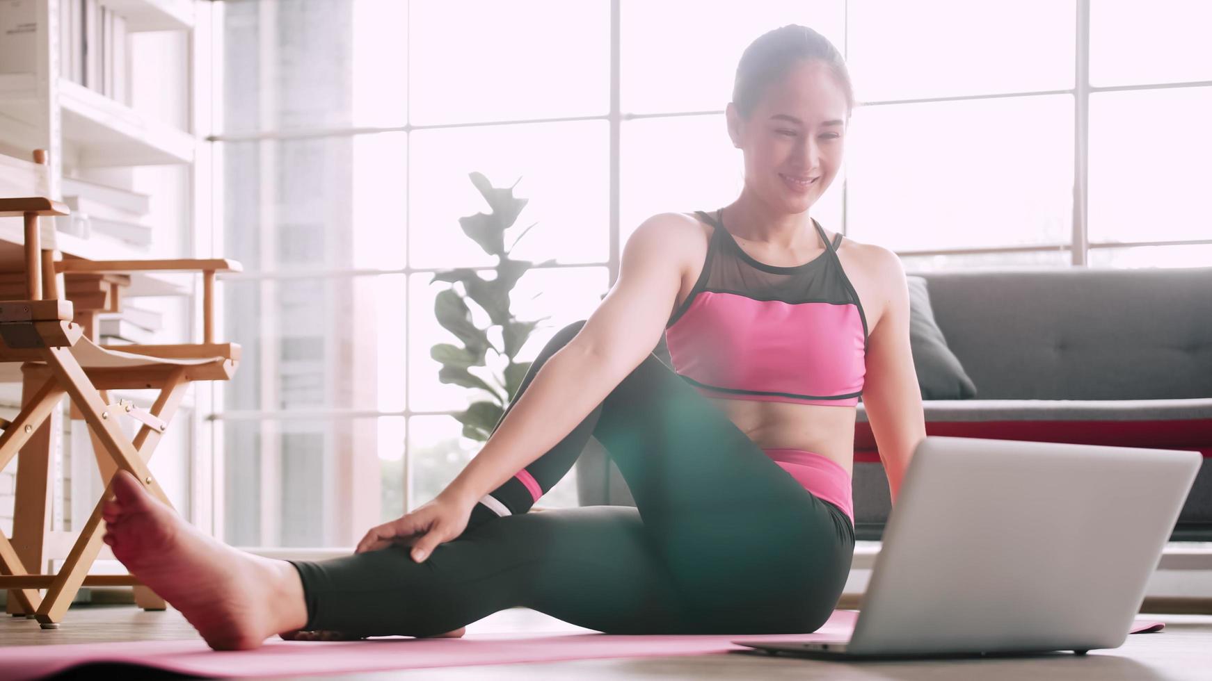 una chica asiática está practicando yoga en línea desde casa. foto