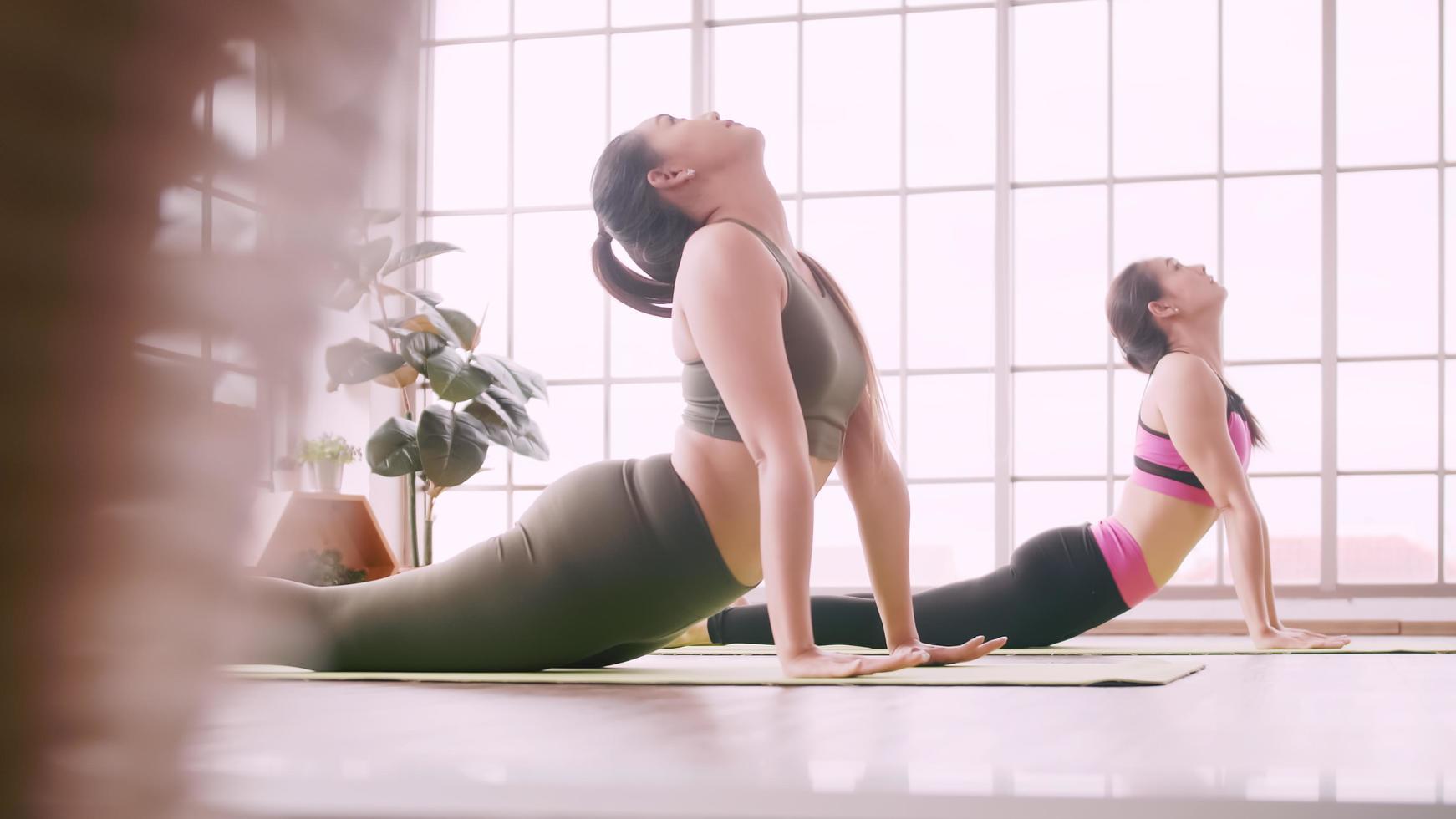 dos chicas asiáticas haciendo ejercicios de yoga en casa. foto