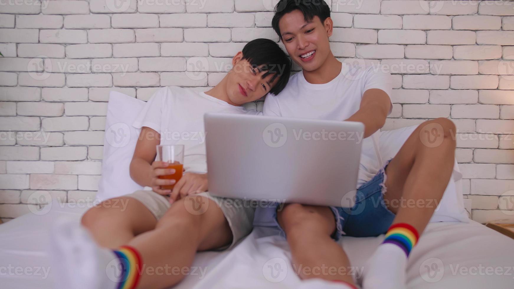 Happy gay Asian couple spending time together in bed at home. photo