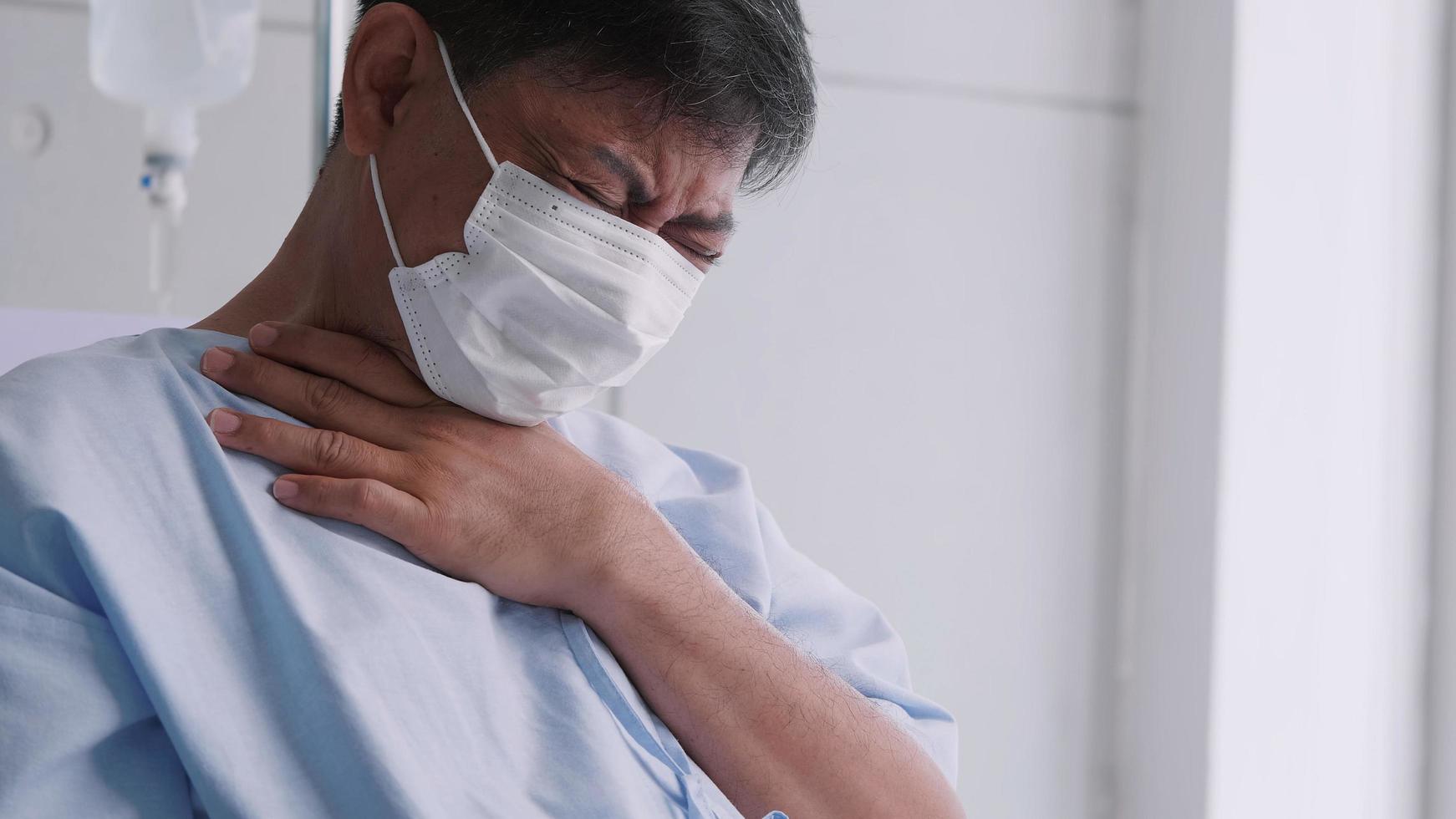 Asian old man is hospitalized with COVID-19. Old male patient wearing a medical mask sits on the patient's bed. photo