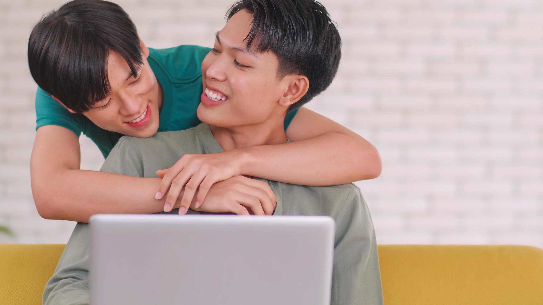 Asian gay takes care of his partner while working on his laptop at home. photo