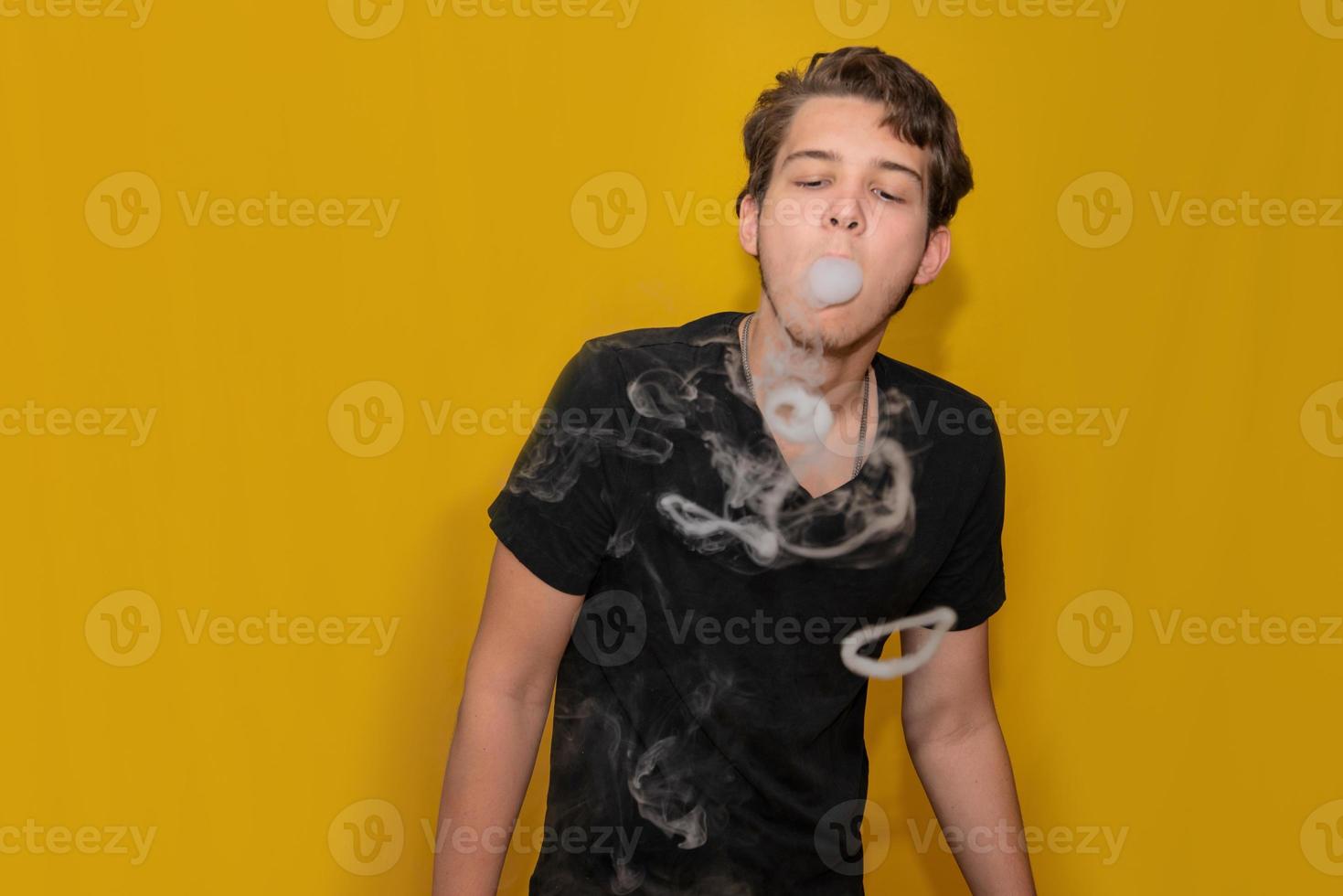 The concept of popularization of vaping. Vaping young man lets out a some rings of steam or smoke square cropping view. Young man releases steam rings from his mouth. photo