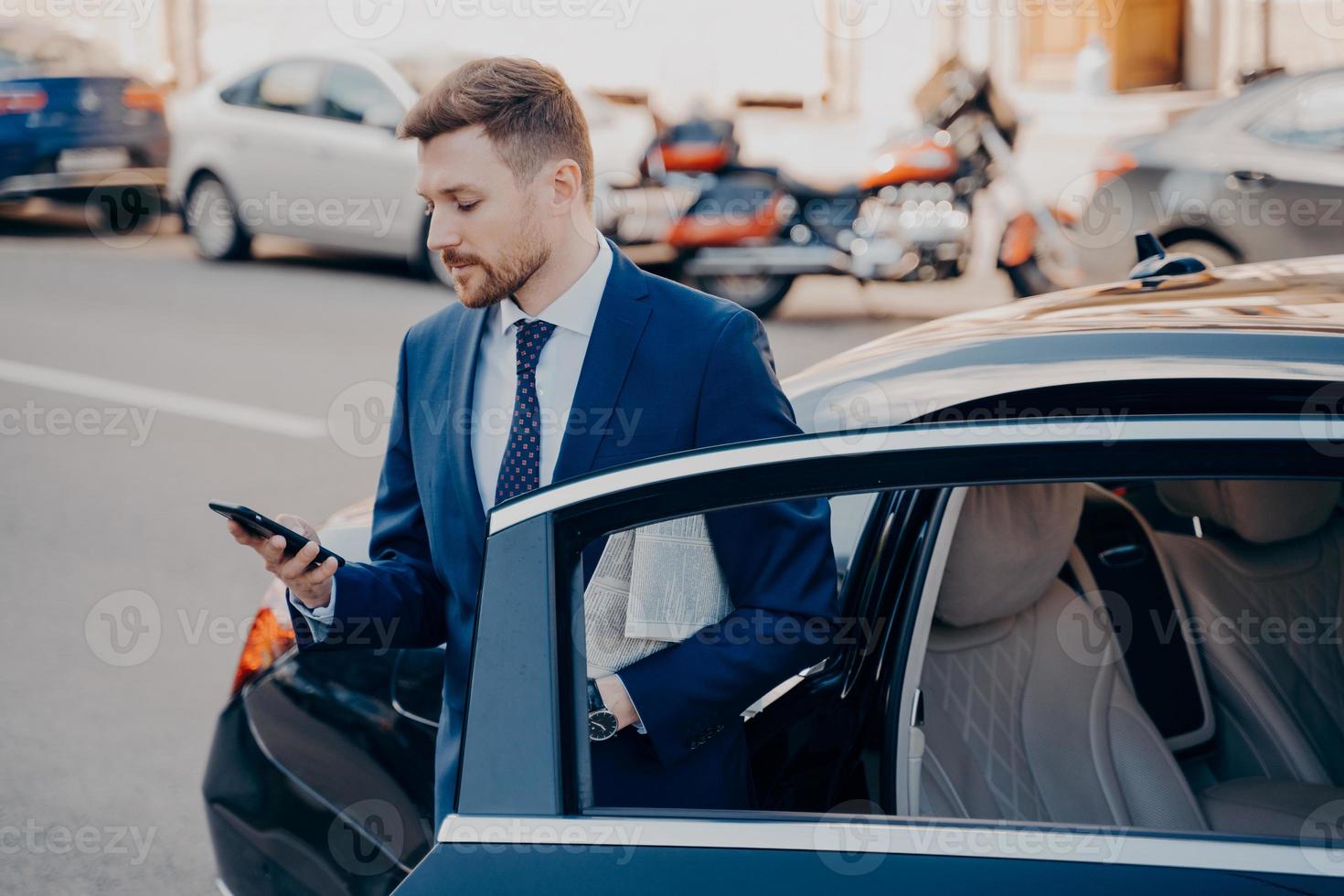 Successful executive manager in formal stylish tuxedo suit getting out of car photo