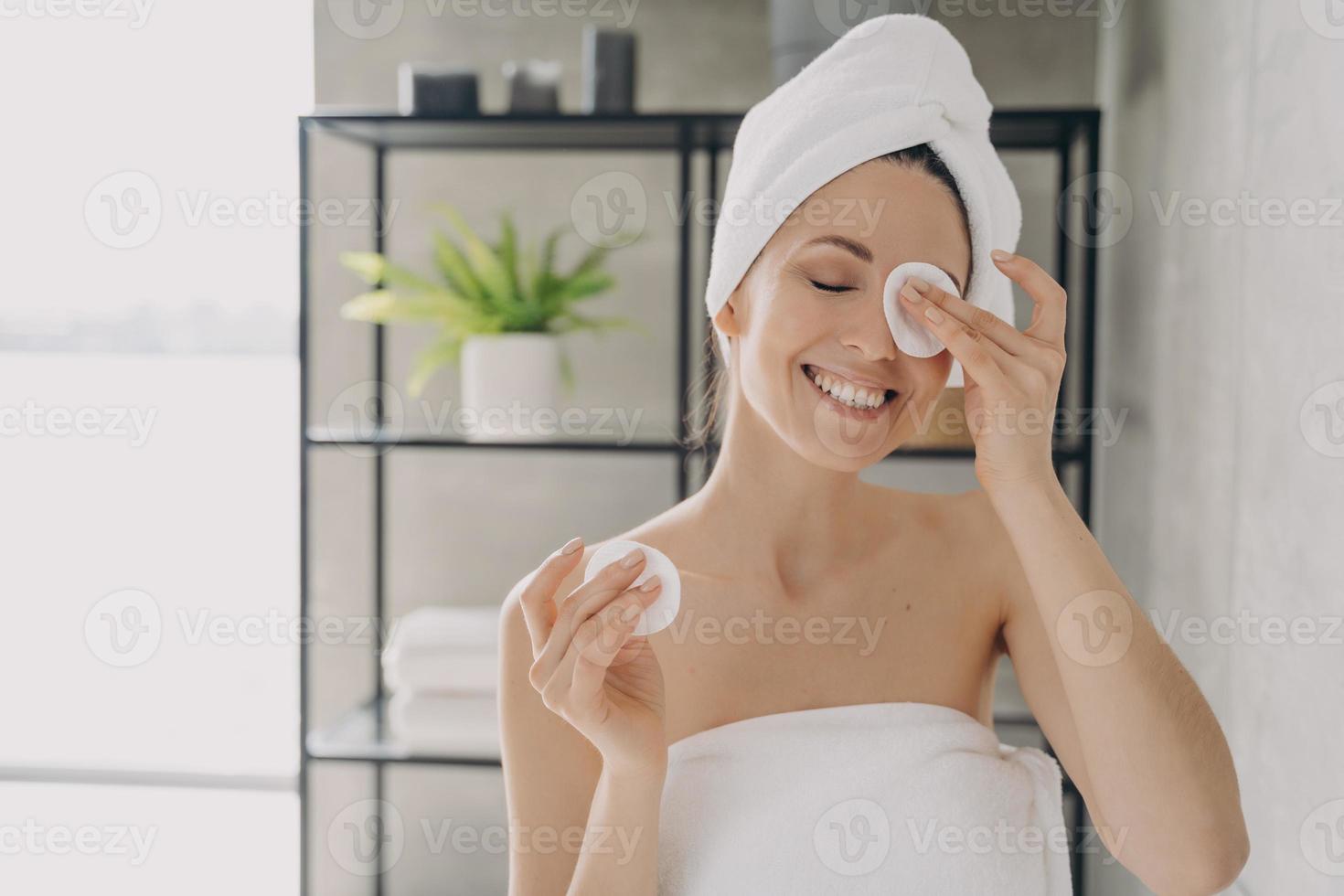 la chica caucásica está limpiando la piel con loción facial en el baño. Cuidado de la piel delicada y purificante. foto