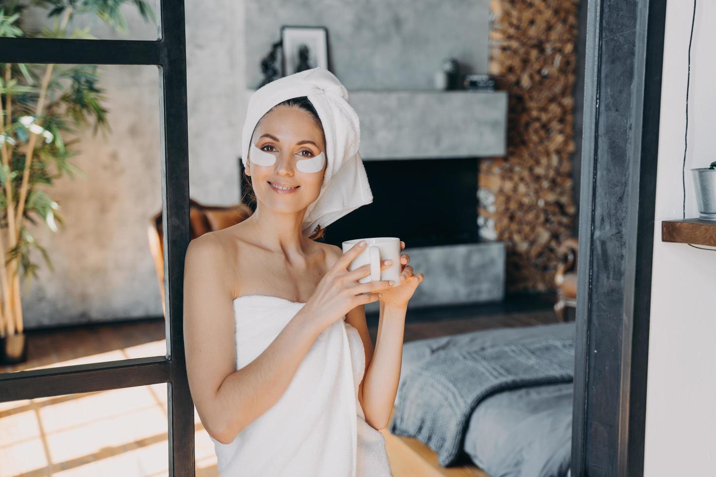 Girl applies lifting eye patches relaxing with cup of tea. Weekend morning at luxurious spa resort. photo