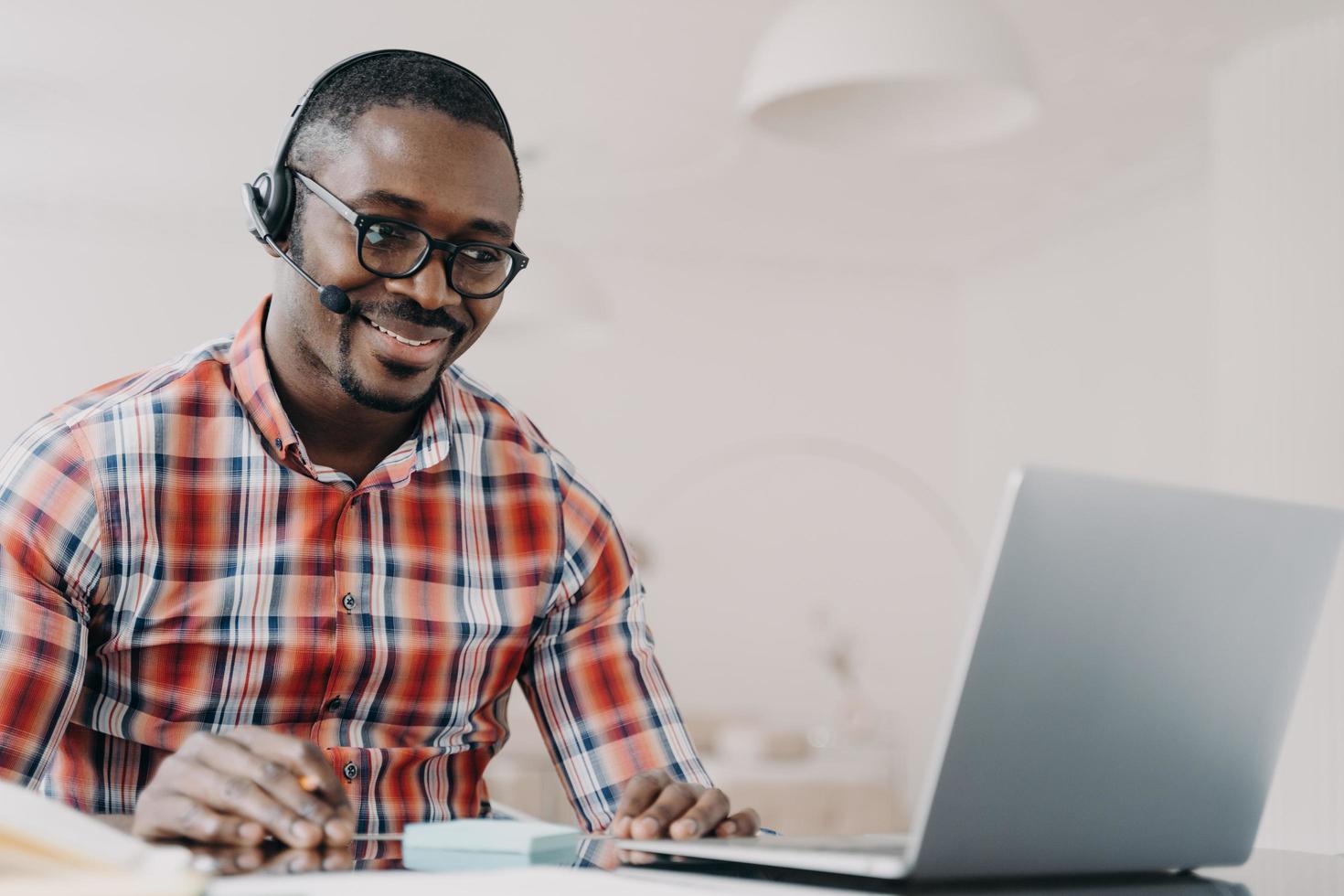 African american man support services technician in headset works at laptop communicates with client photo