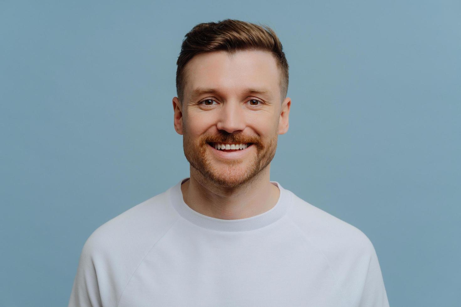 Young happy handsome unshaven man in casual wear smiling at camera photo