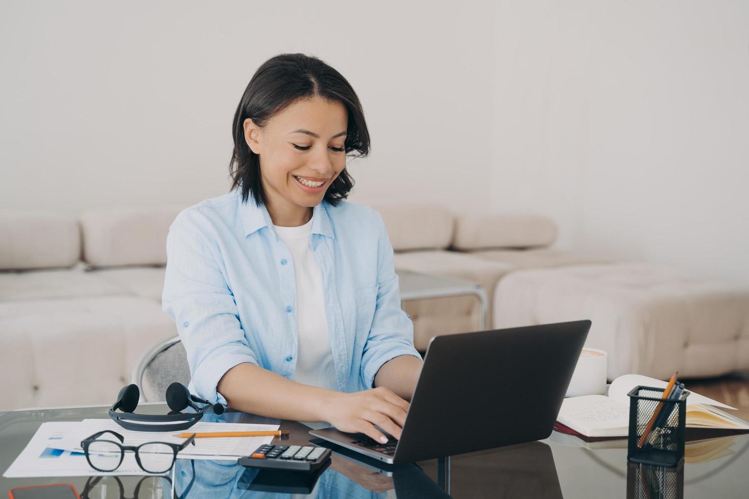 Happy woman is typing text on computer. Lady is chatting, having conversation with colleague. photo